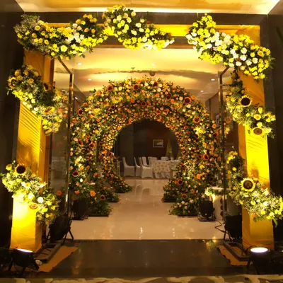 A magnificent entrance for a Haldi ceremony, featuring a grand archway completely covered in vibrant sunflowers and yellow blooms, creating an immersive floral experience.