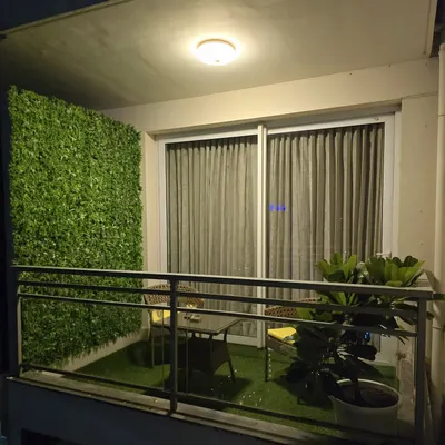 The perfect small balcony makeover. A lush artificial grass floor and a dense green wall turn this into a private, positive space.