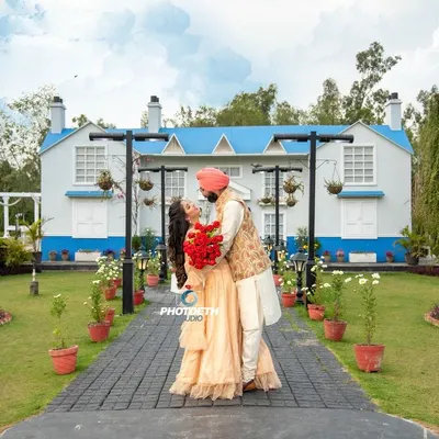 A beautiful, wide-angle shot of a couple at a picturesque location. The grand house and manicured garden provide a perfect backdrop for a classic and romantic pre-wedding photo.