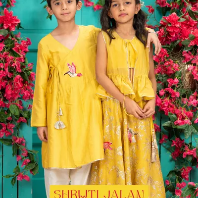 Sunshine yellow is a perfect color for festive celebrations. This brother-sister set features a girl's peplum lehenga and a boy's Angrakha-style kurta, both adorned with delicate bird embroidery and tassels for a coordinated, playful look.