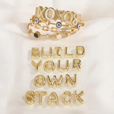 Stacking made easy. This shot shows you how to build your own stack with our XOXO mesh bracelet and evil eye charm bangles, with loose letters spelling it all out.
