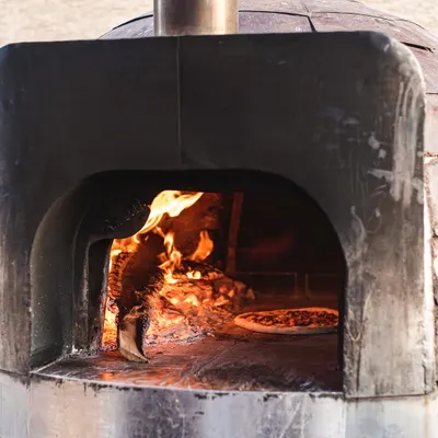 A glimpse inside our mobile wood-fired oven, where the magic happens. The intense heat creates that signature leopard-spotted char on the crust, cooking pizzas in just 90 seconds.