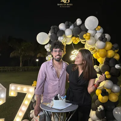 A happy client celebrating their 27th birthday with our decor. The outdoor setup with black, white, and yellow balloons and marquee numbers created the perfect backdrop for their special night.