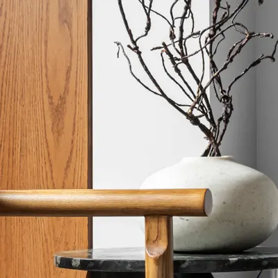 There is a timelessness in the pairing of raw stone and natural wood. This composition of a dark marble side table, a warm wood chair, and sculptural dried branches explores the balance of strength and warmth, texture and tone.