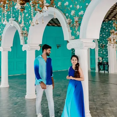 A candid moment in a beautiful palace setting. The ombre blue gown complements the man's coordinated shirt, creating a stylish and modern look for this couple's photoshoot.