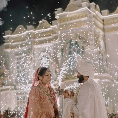 We love capturing the grand scale of your celebration. This stunning varmala moment, set against a beautifully lit palace facade with a brilliant display of cold pyro fireworks, highlights our expertise in filming large, destination weddings and turning them into spectacular cinematic events.