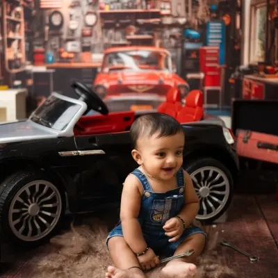 The happiest little mechanic in his own garage. This detailed setup, complete with a mini car and tools, is perfect for a fun and unique sitter session.
