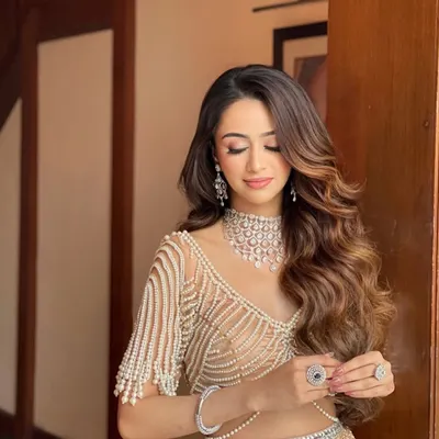 A glamorous look perfect for a reception or sangeet. I created these voluminous, side-swept Hollywood waves to complement the intricate pearl and diamond jewelry, ensuring the hair feels as luxurious as the outfit.