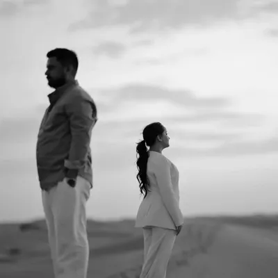A powerful and artistic black and white portrait in the desert. The composition and their expressions create a moody, cinematic, and deeply contemplative image.