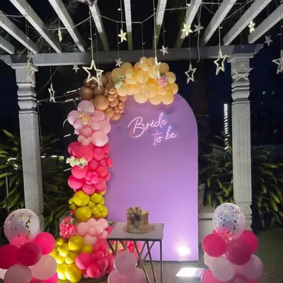 A lovely 'Bride to be' decoration on a terrace, featuring a purple backdrop, a colorful balloon garland, and hanging star lights.