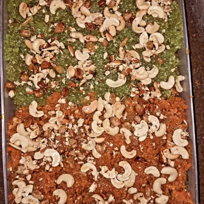 Green and orange sweets share a tray, with cashews and other nuts spread across the top of our catering desserts.