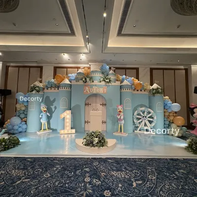 A magnificent, wide shot of the Disneyland castle stage setup for Aviraj's first birthday. The design includes a light-up number one and character cutouts of Donald and Daisy Duck.