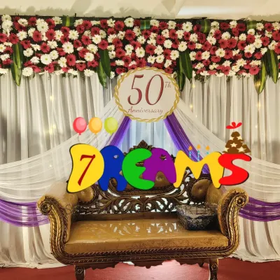 This stage was for a 50th wedding anniversary. I used a backdrop of white and purple drapes, topped with a dense arrangement of fresh flowers and a custom '50th Anniversary' sign.