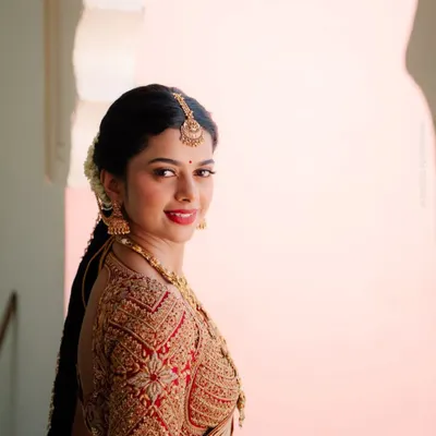 This red bridal blouse showcases heavy zardosi and sequin embroidery, crafted to perfectly match an off-white Kanchivaram saree. The detailed work on the sleeves makes it a standout piece for any muhurtham ceremony.