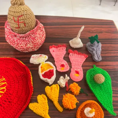 All the individual, hand-crocheted elements of my pooja thali set laid out, including a kalash, betel leaf, flowers, and other traditional items.