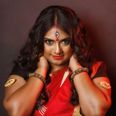 A powerful pose from our Devi-themed shoot. The makeup features intense, kohl-rimmed eyes, a bright red bindi with the third-eye detail, and a bold lip to create a look of divine strength and beauty.