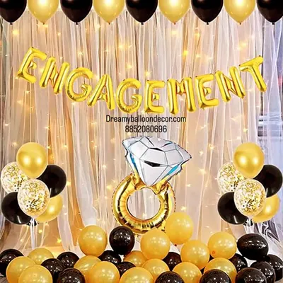 A classic and elegant engagement party backdrop. The black and gold theme, 'Engagement' foil banner, and giant ring prop create a perfect photo corner for you and your guests.