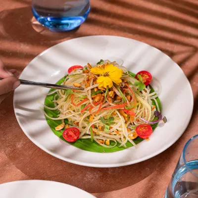 A beautifully plated papaya salad for a restaurant shoot. My styling focused on the delicate arrangement of ingredients, garnished with an edible flower, to present the dish as a light, fresh, and gourmet option.