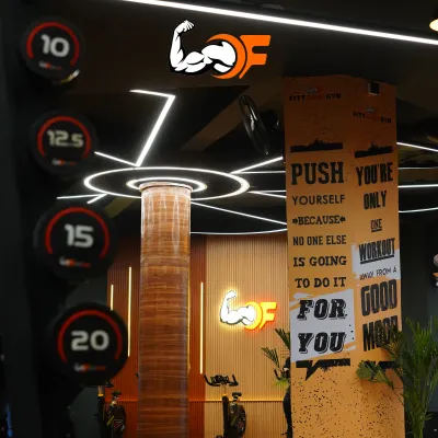 An inside look at our gym's motivating atmosphere, featuring our iconic logo, modern lighting, and inspirational wall art that reminds you to push yourself.