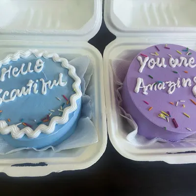 Two of our custom bento cakes with uplifting messages, "Hello Beautiful" and "You Are Amazing." These mini cakes are perfect for gifting and spreading joy.