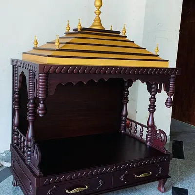 A full view of a traditional, handmade wooden mandir. This unique piece features intricately turned pillars, carved details, and a tiered roof with golden accents, creating a truly special place for prayer.