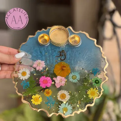 A beautiful blue resin pooja thali, handcrafted with real flowers, an Om symbol, and brass bowls for your daily rituals.