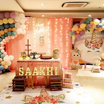 A full view of a unicorn-themed stage I designed, featuring a pastel rainbow balloon arch and custom unicorn cutouts. The personalized light-up marquee letters and unicorn-themed floor mat tie the entire magical concept together for a picture-perfect celebration.
