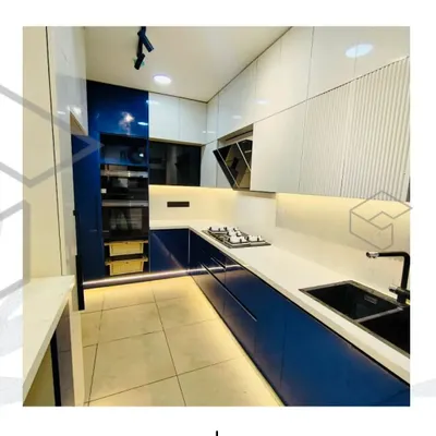 This U-shaped modular kitchen combines bold blue acrylic cabinets with crisp white overheads for a striking, modern look. I focused on an efficient layout, integrating appliances seamlessly and using under-cabinet LED lighting to brighten the workspace.