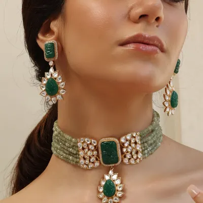 Welcome to Emrosia. This stunning set features a carved emerald choker with floral polki motifs and matching drop earrings, embodying the soul of the collection.