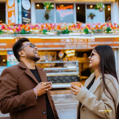 A candid shot of a couple sharing a laugh over a cup of chai on Mussoorie's Mall Road, capturing a genuine and joyful moment.