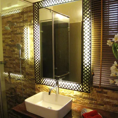 For this bathroom renovation, the focus was on creating a warm and luxurious atmosphere through texture and light. I designed a custom backlit mirror with a traditional jaali pattern frame, which becomes the centerpiece. This is set against a natural stone tile wall to add depth and character to the vanity area.