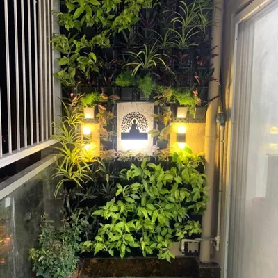A closer look at a custom balcony vertical garden at night. The warm, strategically placed lighting highlights the plant textures and the central art piece, proving that your garden can be enjoyed day and night.