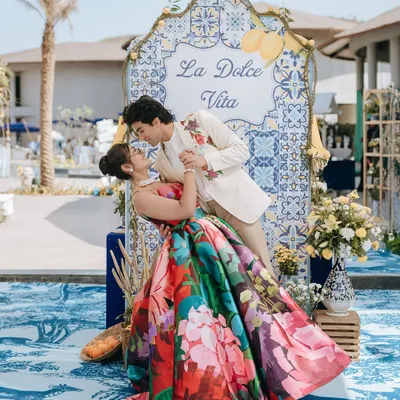 A vibrant and romantic shot from a "La Dolce Vita" themed carnival event. The couple's colorful outfits and the beautiful decor showcase a fun and stylish pre-wedding celebration.