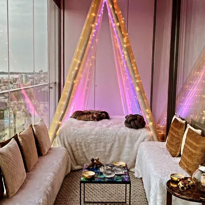 A cozy seating arrangement we created on a balcony with a beautiful city view. The setup includes a teepee-style canopy bed and comfortable floor seating, perfect for a relaxed evening.