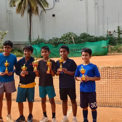A group of our upcoming champions proudly displaying their trophies on our clay courts. This photo captures the joy and success of Jaideep, Lawan, Amish, and Hamsini after a great tournament performance.