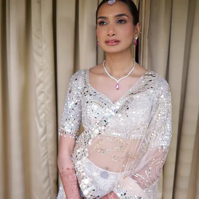 For a Goa wedding, you have to be ready for sun and humidity. We matched her ivory mirror-work lehenga with a luminous, long-lasting base, soft champagne lids, and a sleek bun with baby's breath.