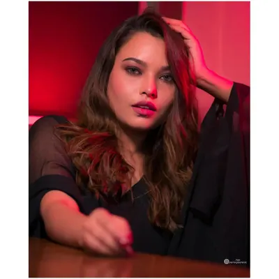 A close-up portrait using red gel lighting to create a bold, cinematic feel. The focus is on the intense expression and the play of light and shadow.