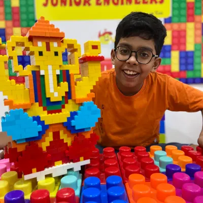A student beams with pride next to his large, colorful LEGO Ganesha. Our themed workshops blend cultural celebration with hands-on STEM learning.