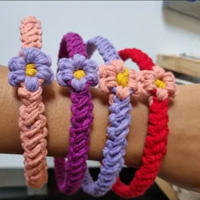 A collection of my floral macrame headbands worn on the arm to show their flexibility and vibrant colors. Each one is hand-knotted with a delicate flower accent, perfect for festivals or everyday style.