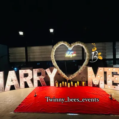 A classic and bold proposal setup. We use large, bright marquee letters that spell out "MARRY ME" with a beautiful floral heart and candles to create a grand romantic gesture.