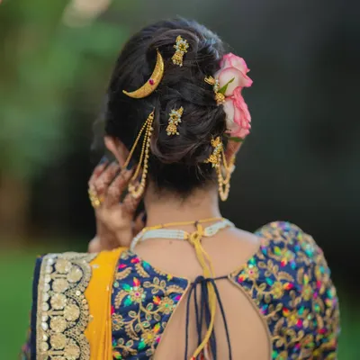 A detailed view of a modern messy khopa, adorned with a delicate chandrakor pin and fresh flowers. This style combines tradition with a contemporary, softer feel.