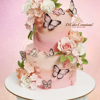 A beautiful two-tier cake in shades of pink, adorned with delicate sugar flowers and wafer paper butterflies. This design is perfect for birthdays, bridal showers, or any elegant celebration.