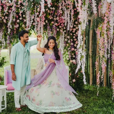 A couple dancing under a breathtaking canopy of hanging wisteria, creating a fairytale moment for their garden-themed celebration.