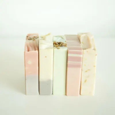 A beautiful stack of my soaps, showcasing the variety of natural colors and textures. From left to right: Lavender Patchouli, Neroli Patchouli, Eucalyptus Tea Tree & Rosemary, Flower Market, and Jasmine Calendula.