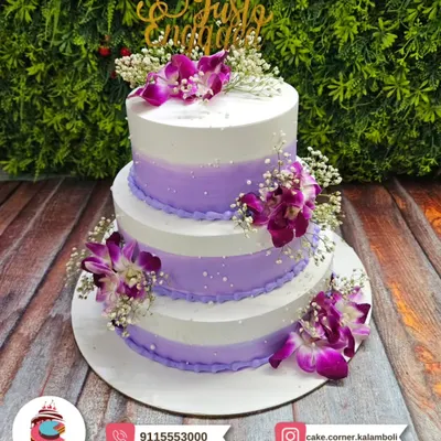 A stunning three-tier engagement cake in shades of purple and white, adorned with beautiful fresh orchids. The "Just Engaged" topper makes it the perfect centerpiece for your special announcement.