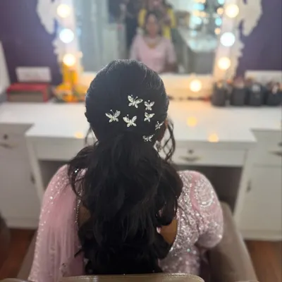 It's all in the details. This shot highlights a chic and modern hairstyle for a reception, featuring a textured ponytail adorned with delicate butterfly clips, perfect for brides who want a touch of whimsy.