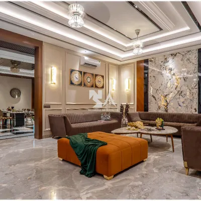 In this drawing room, we used an exotic stone slab as a dramatic backdrop, highlighted by ambient lighting. The rich textures of the stone, paired with plush brown sofas and a vibrant orange ottoman, create a space that is both opulent and welcoming.