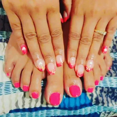 A great example of a coordinated set. The toes feature a clean and simple solid hot pink gel polish, which complements the more intricate pink French manicure on the hands, creating a balanced and stylish look.