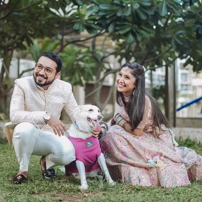 A happy couple in elegant ethnic wear posing with their adorable dog in a green park. I love when couples bring their pets along, as it adds a personal and joyful touch to the pre-wedding photos.