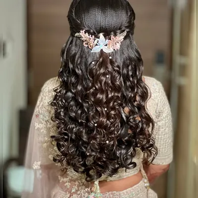A stunning example of a half-up, half-down hairstyle with voluminous curls, perfect for a reception. The look is completed with a beautiful pearl and crystal hair accessory.